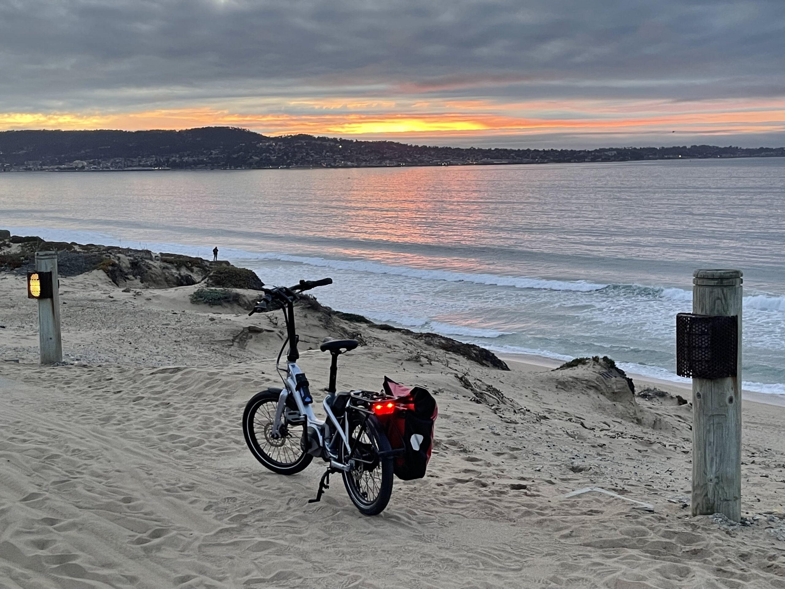 A bicycle resting on the beach beside Monterey Bay at sunset